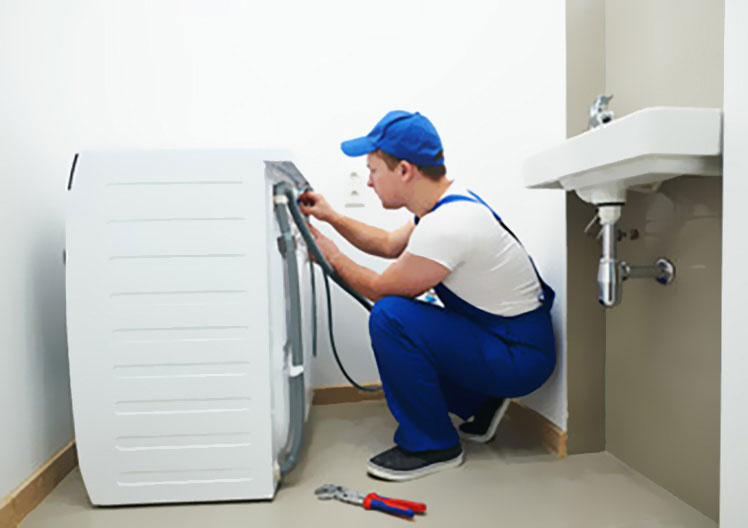 Techniker repariert Waschmaschine am Wasseranschluss